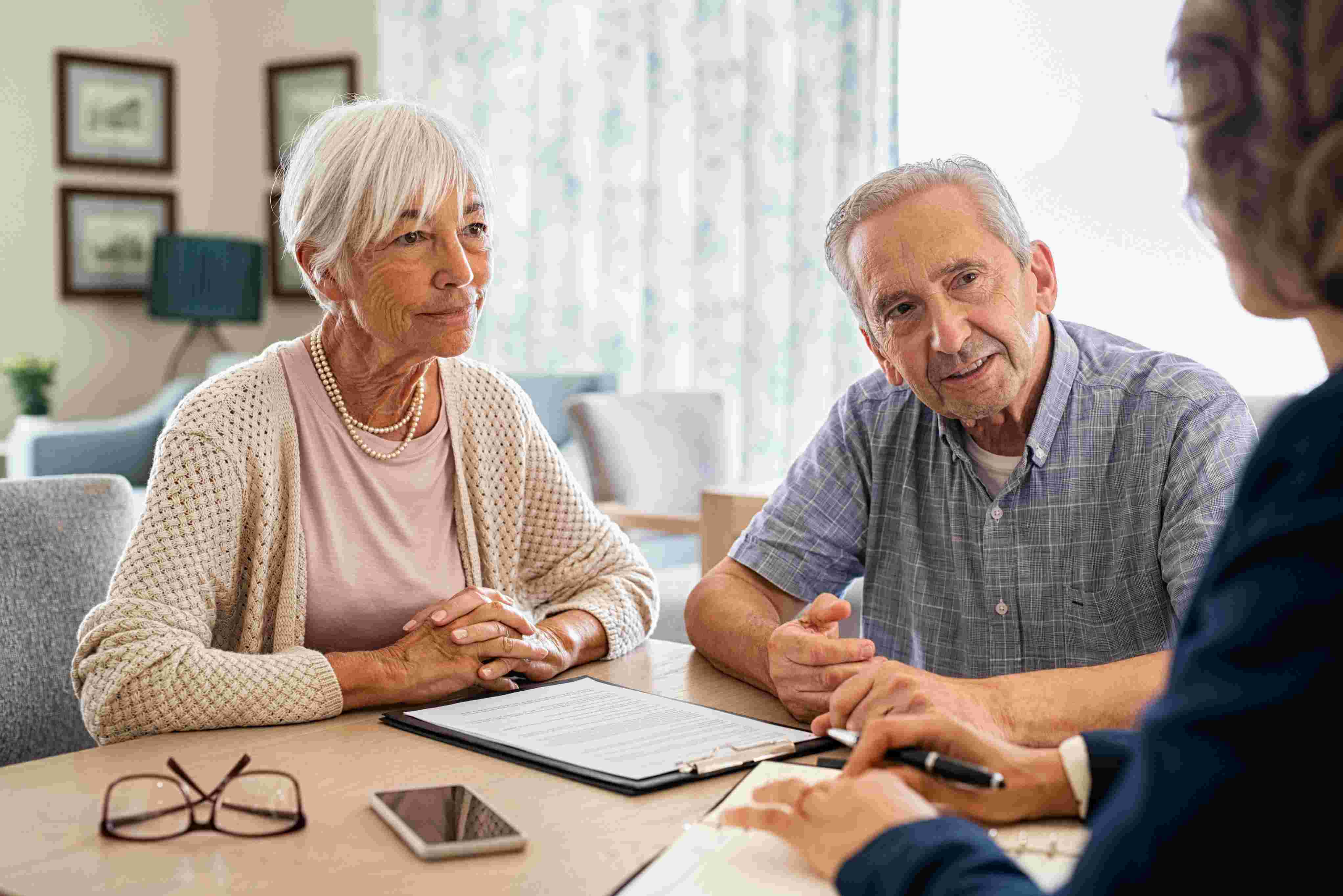 A professional advisor offers support and guidance to an elderly couple at their table, representing personalised in-home care planning and services navigation.